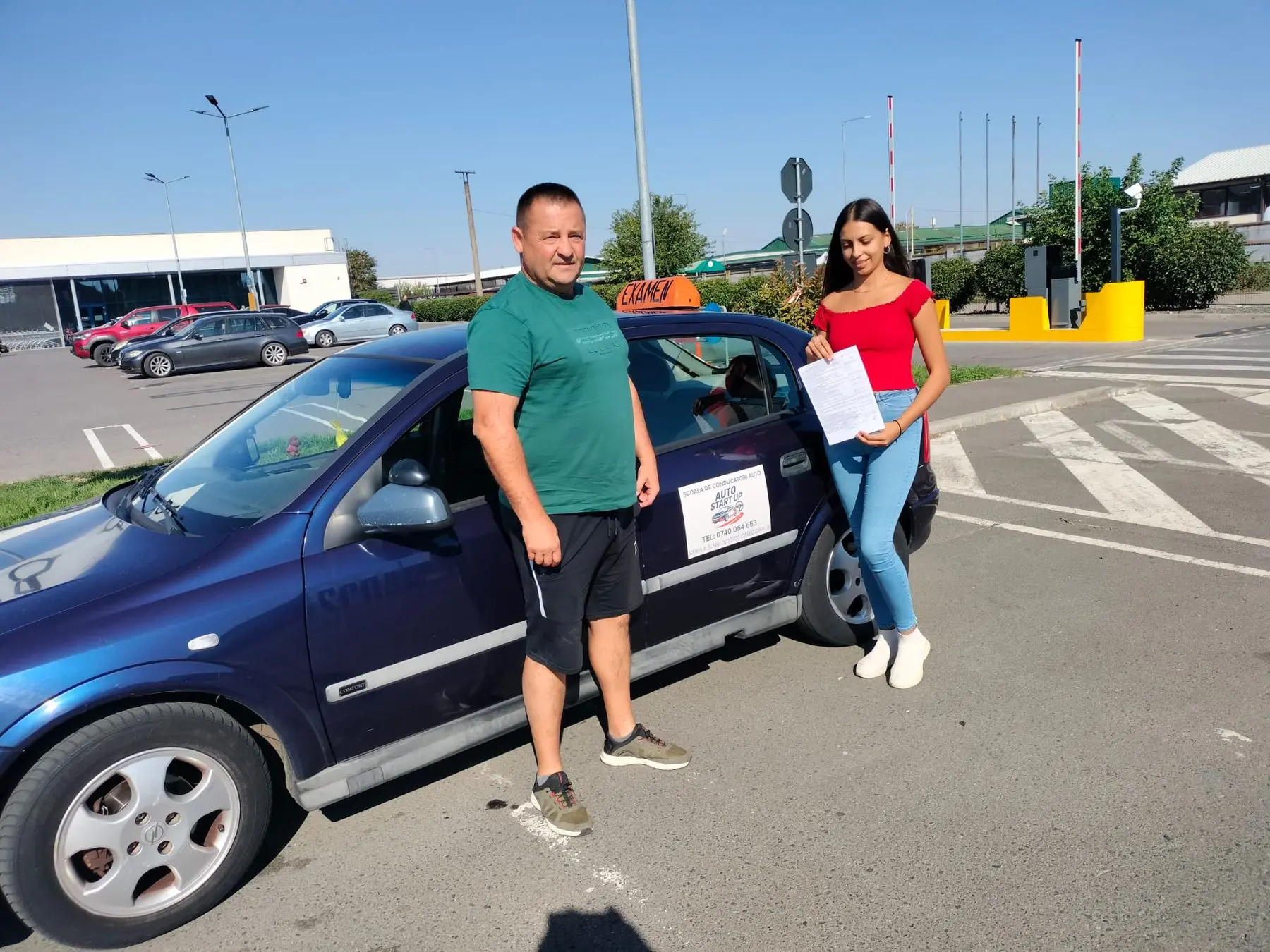 Instructor și cursantă lângă mașina școlii